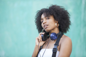 cool urban black woman listening music on the street