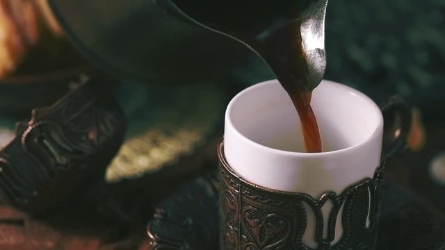 Pouring turkish coffee into traditional embossed metal cup