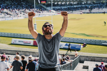 Fototapeta .Young man enjoying a rugby match at the stadium on a sunny autumn day. Screaming, celebrating and encouraging your team. Lifestyle. obraz