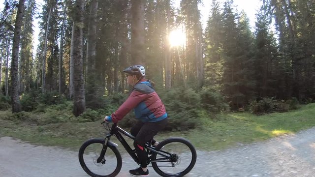 Female mountain biker riding ona  sunny fall seasoned forest road