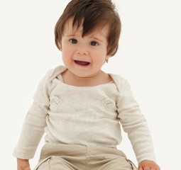 Funny baby sitting on the floor, isolated over white