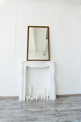 white fireplace with a mirror above it in an empty room