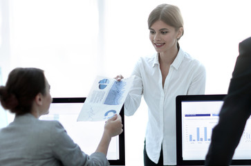 senior Manager, handing the employee a document with financial data.