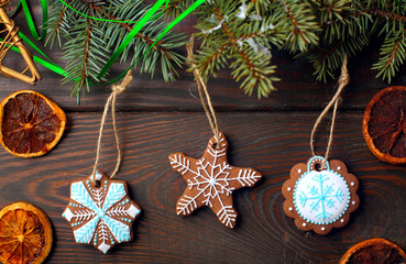 Gingerbread cookies stars hanging on spruce branches against a wooden background.Christmas background