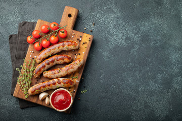 Fried sausages with sauces and herbs on a wooden serving Board. Great beer snack on a dark...