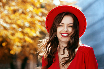 Outdoor close up portrait of beautiful happy smiling girl with long hair, red lips, wearing stylish hat, dress, posing, walking in street. Autumn fashion, lifestyle concept. Copy, empty space for text