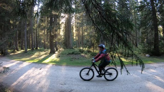 4K. Female mountain biker passing the camera with  forest at the background