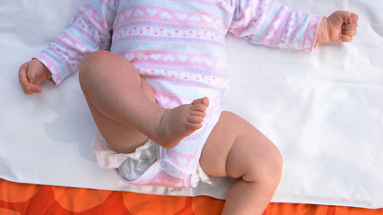Newborn baby girl lying on back. Tiny bare legs of infant child. Birth of new life and parenting.