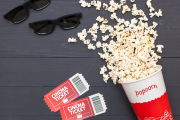 Movie time, flat lay. Cinema minimal concept. Composition on a black wooden background with a popcorn, 3D glasses and movie tickets with space for text, context