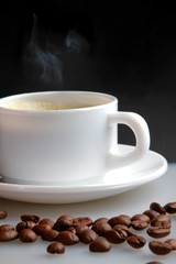 Cup of coffee with coffee beans next to it