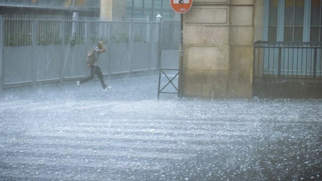 Extreme weather hail rain storm on the streets of Paris man hiding from hail