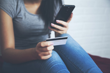 woman take credit card and look phone on the bed
