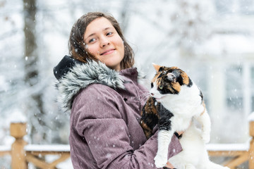 Closeup of young woman holding angry, scared meowing calico cat outside, outdoors on house deck, in...