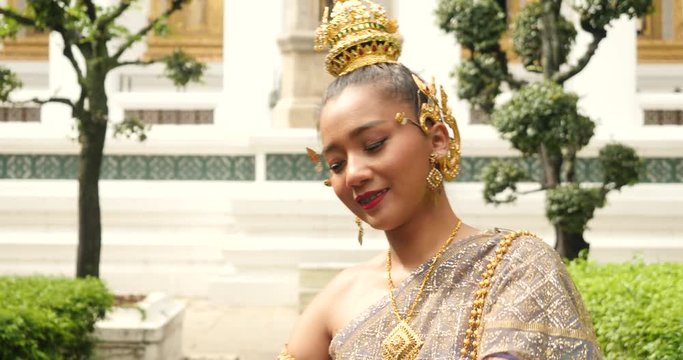 beautiful asian woman in thai traditional dress dancing traditional thai dance in Thai buddhist temple in bangkok wat suthat. outdoor next to temple