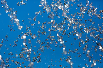Splash of water against the blue sky, liquid refreshing splashes on a blue background.