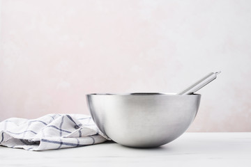 Baking concept. Bowl with a whisk and dishcloth on white marble table over pink background with copy space.