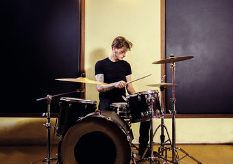 Tattooed man playing drums in studio 