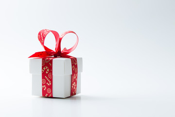 One white gift box tied with a red Christmas theme ribbon isolated on white background