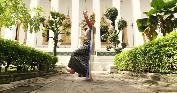 beautiful asian woman in thai traditional dress dancing traditional thai dance in Thai buddhist temple in bangkok wat suthat. outdoor next to temple