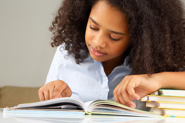 dark-skinned schoolgirl reading a book doing homework