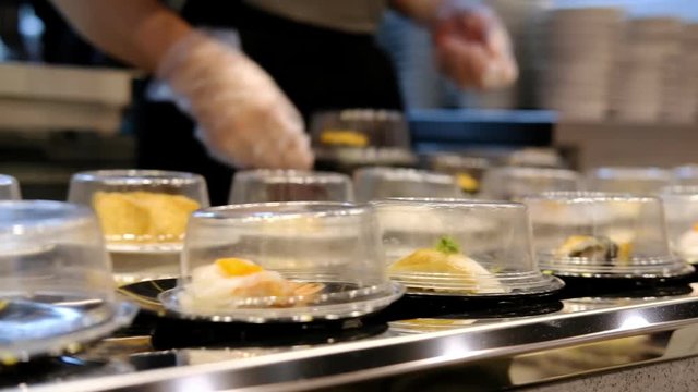 Chef putting food on conveyor belt sushi in japan restaurant