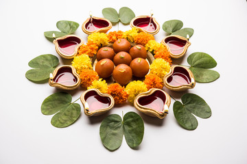 Happy Dussehra / Vijayadashami / Ayudh Puja greeting card using apta/Bauhinia racemosa/Bidi leaf and indian sweet Rasgulla or Gulab Jamun for Navaratri along with Diya/oil lamp