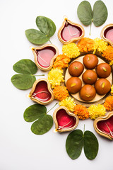 Happy Dussehra / Vijayadashami / Ayudh Puja greeting card using apta/Bauhinia racemosa/Bidi leaf and indian sweet Rasgulla or Gulab Jamun for Navaratri along with Diya/oil lamp
