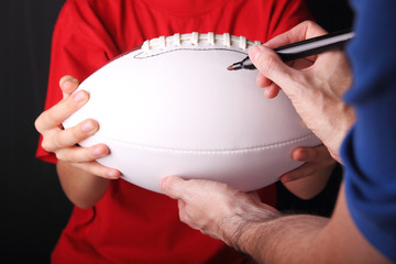 Young football fan getting an autograph on a new white blank football - obrazy, fototapety, plakaty