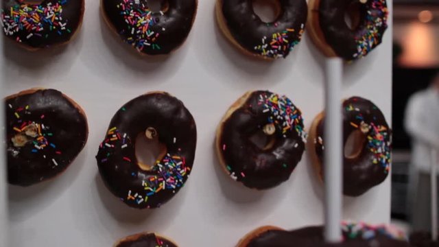 Chocolate doughnuts with rainbow sprinkles hanging from spokes
