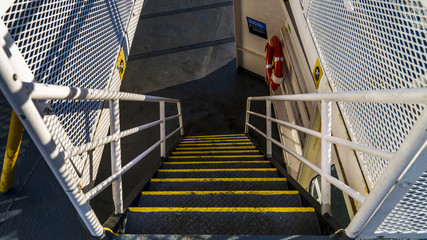 Metal staircase on a ship with lifering and handrails.