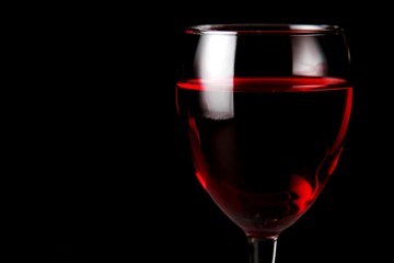 Dark background with a wine glass full of rose wine