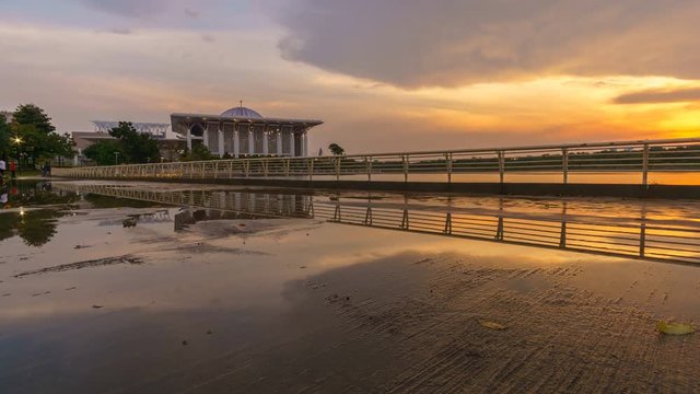 Reflection of sunset on wet sidewalk with Sultan Mizan Mosque Time lapse Pan Up