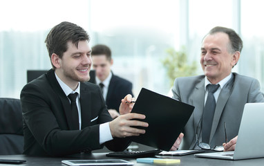 adult businessman discussing financial documents with a young colleague.