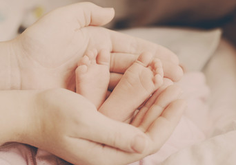 Obraz na płótnie Canvas newborn baby feet in mothers hands