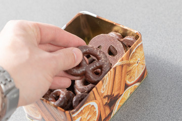 Hand picking a gingerbread pretzel out of a cookie box for christmas