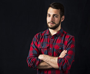 young guy in checkered shirt with a beard on a black background