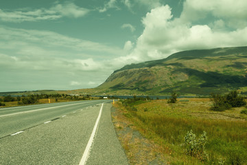 Beautiful icelandic deserted roadway along ocean fiord and green hills. Copy space.