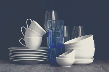 White porcelain dishes and wine glasses. Closeup. Foggy image.