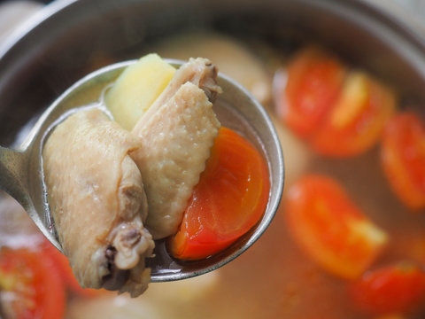 Homemade chicken soup. Chicken soup with tomato, potapo and coriander in a ladle.