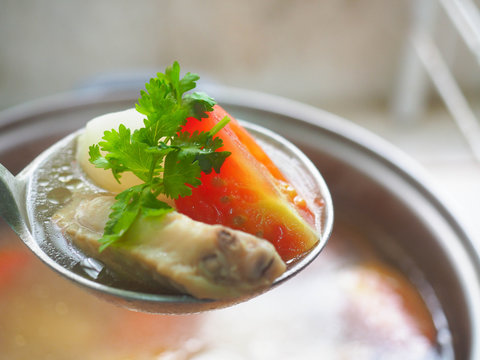 Homemade chicken soup. Chicken soup with tomato, potapo and coriander in a ladle.