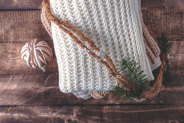 Warm, pastel clothes, knitted, pastel-colored scarves and a ball of knitting yarn on a wooden background. Winter, autumn clothes.