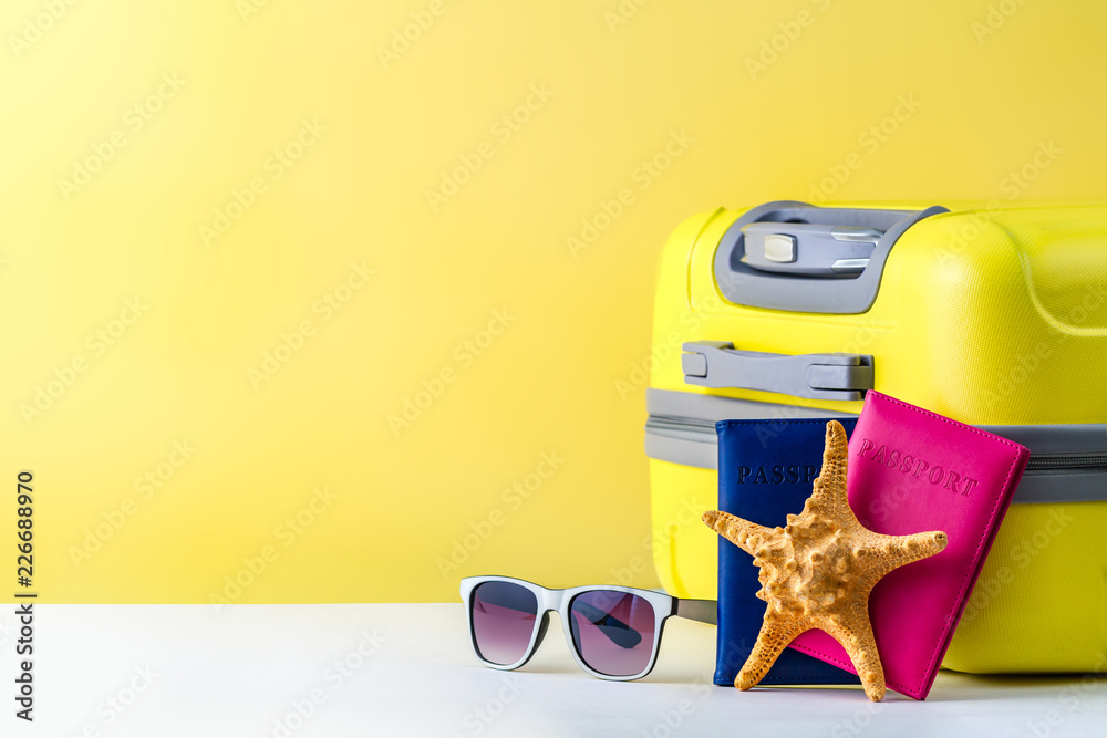 Wall mural a bright, yellow travel suitcase, passport, sunglasses and starfish on a yellow background. travel c