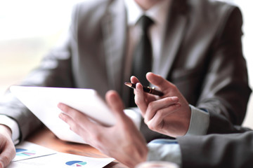 Close-up of business partners discussing document in touchpad