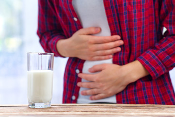 A woman feels bad, has an upset stomach, bloating due to lactose intolerance. Dairy intolerant person. Health care concept. Lactose intolerance and dairy products - obrazy, fototapety, plakaty