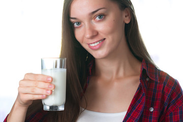 A young, attractive, smiling woman holds in her hands a glass of fresh milk. Dairy products
