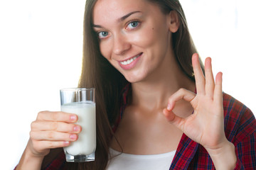 A young, attractive, smiling woman holds in her hands a glass of fresh milk. Dairy products