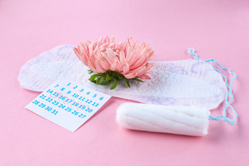 Pads and tampons for menstruation, female calendar and a pink flower on a pink background. Hygiene care during critical days. Regular menstrual cycle.
