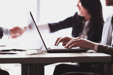 businessman working on laptop on the background of handshake of business partners