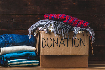 Donation concept. Donation box with donation clothes on a wooden background. Charity. Help for...