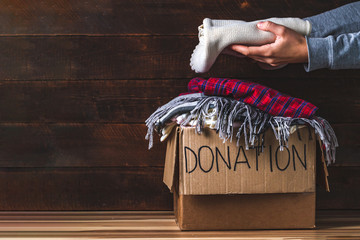 Donation concept. Donation box with donation clothes on a wooden background. Charity. Helping poor...